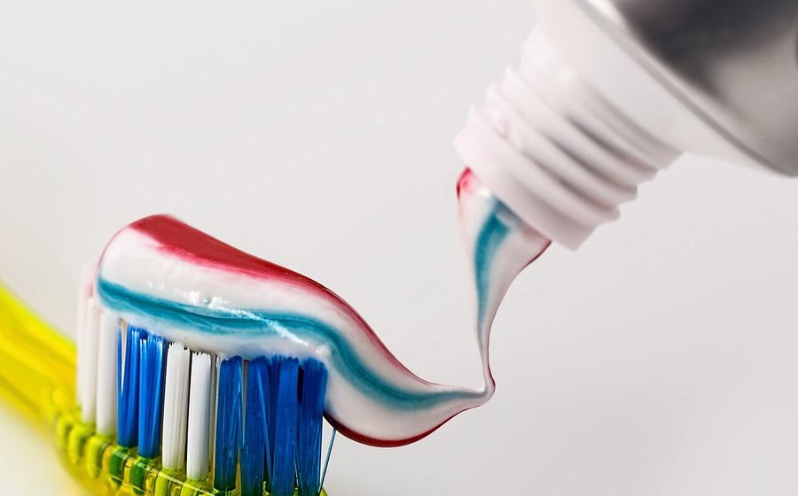 Toothbrush with a ribbon of toothpaste on a clean white background